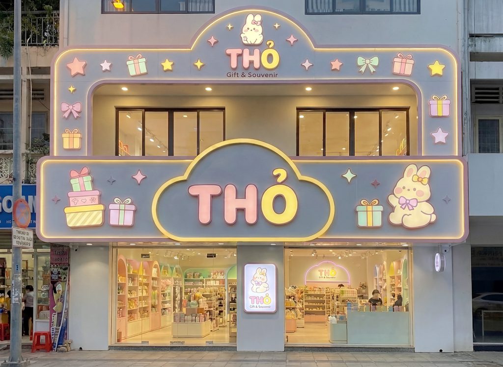 Mặt tiền cửa hàng quà tặng THỎ Gift & Souvenir với bảng hiệu thiết kế dễ thương, màu pastel, logo thỏ nổi bật, trang trí đèn LED viền phát sáng, tạo không gian thu hút và nổi bật vào buổi tối.